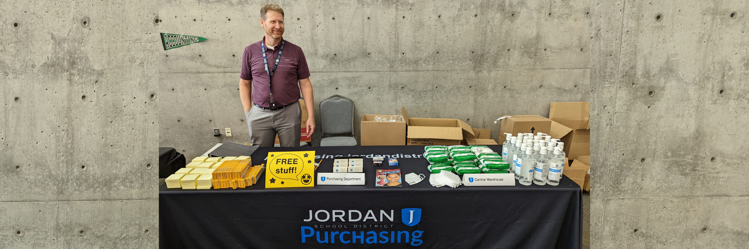 Kurt Prusse smiles behind the Purchasing table with free items for teachers at the 2022 Professional Development Conference.